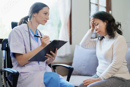 Portrait of a female doctor talking to an elderly patient showing headache.