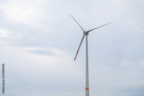 Modern wind turbine renewable energy during daylight with cloudy sky, view from low angle