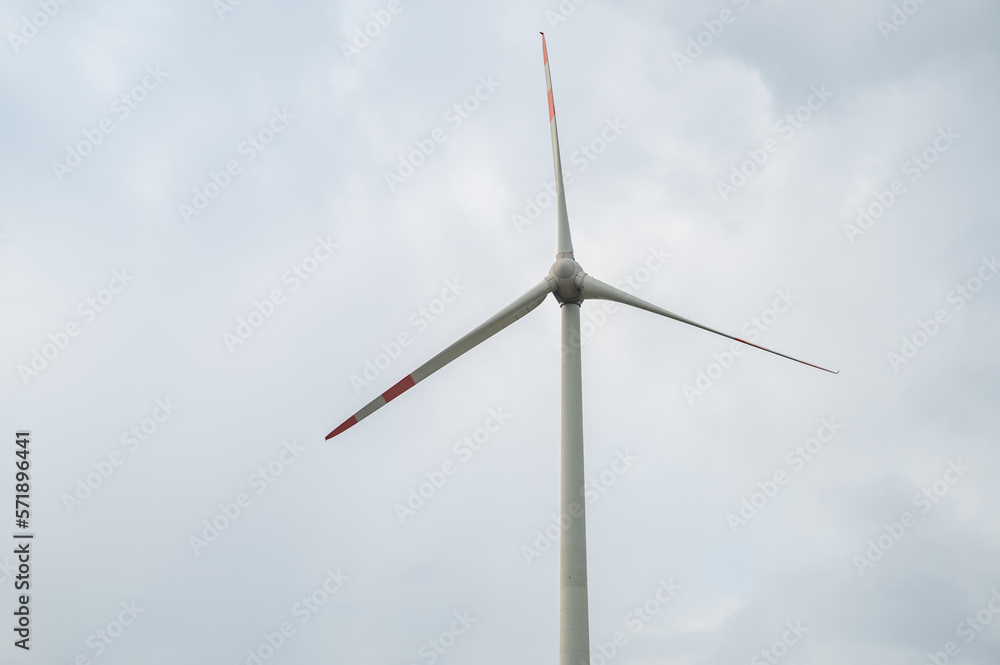 Modern wind turbine renewable energy during daylight with cloudy sky, view from low angle Modern wind turbine renewable energy during daylight with cloudy sky, view from low angle