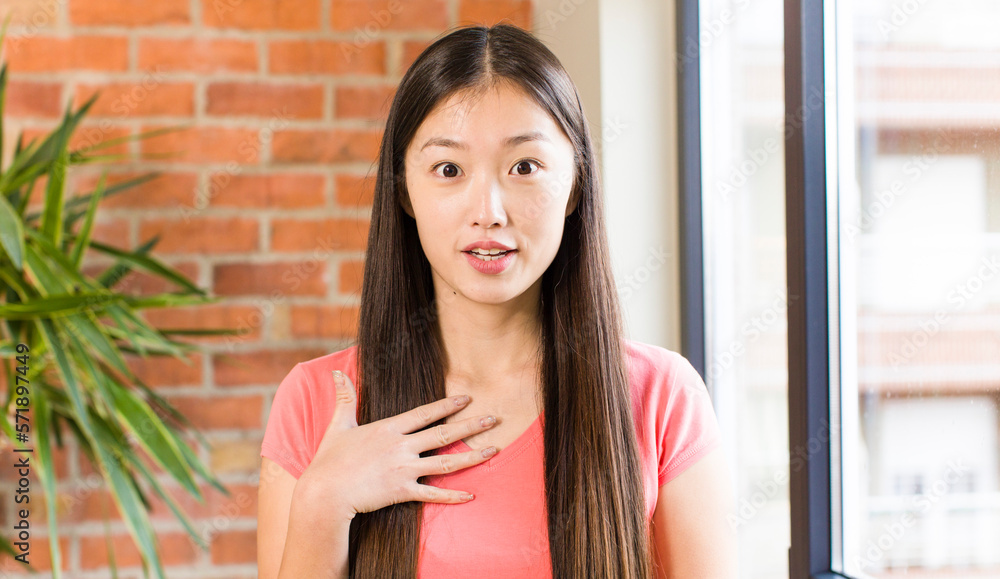 asian pretty woman at home against brick wall with a plant asian pretty woman at home against brick wall with a plant
