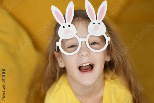 Cute little child girl wearing bunny ears glasses a on Easter day. Easter girl portrait, funny emotions, surprise.