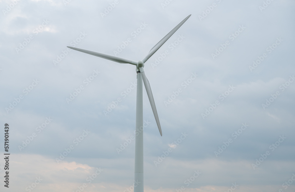 Modern wind turbine renewable energy during daylight with cloudy sky, view from low angle