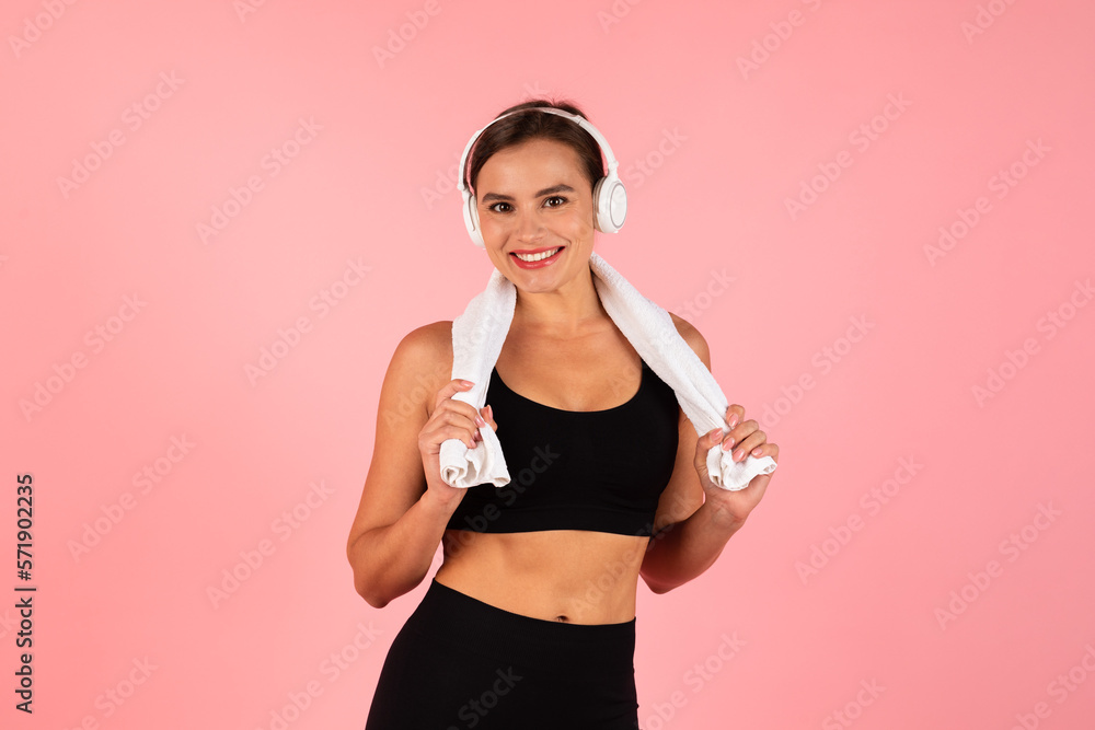 Sporty Young Woman Wearing Headphones Posing With Towel Around Neck After Training Sporty Young Woman Wearing Headphones Posing With Towel Around Neck After Training