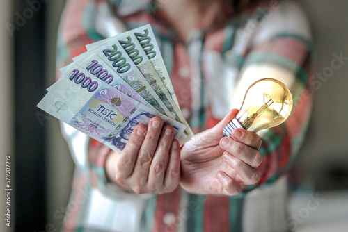 Tableau sur toile Woman showing czech crown banknotes and bulb