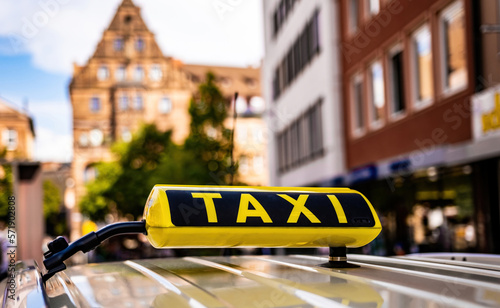 Yellow taxi sign in old historical town of Germany closeup. Cab service board on car at ancient europen city street photo