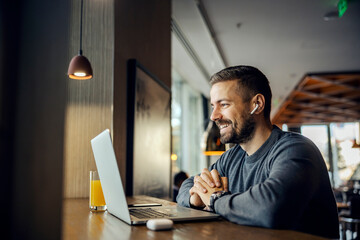 A friendly freelancer is sitting in a coffee shop and having conference call with client.