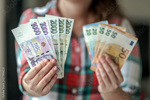 person holding euro banknostes in one hand and in second hand czech crown banknotes of different value photo