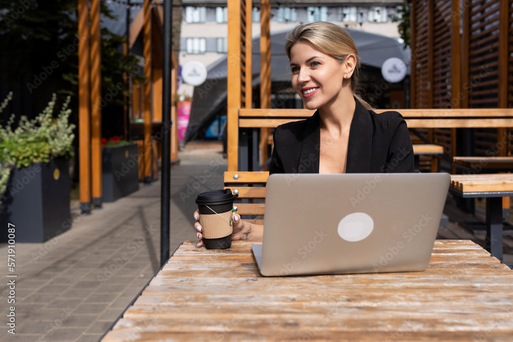 portrait of a successful lady with a cup of coffee and a laptop at work outdoors