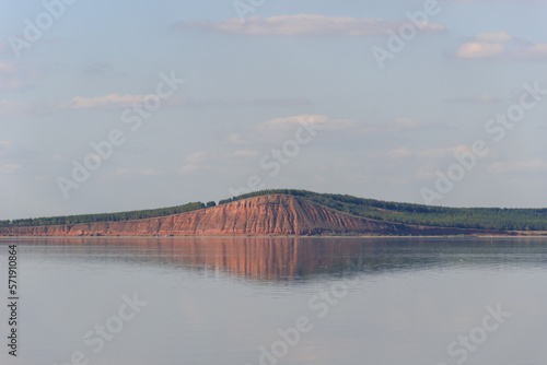 lake with a mountain reflection, red hill with forest on background photo