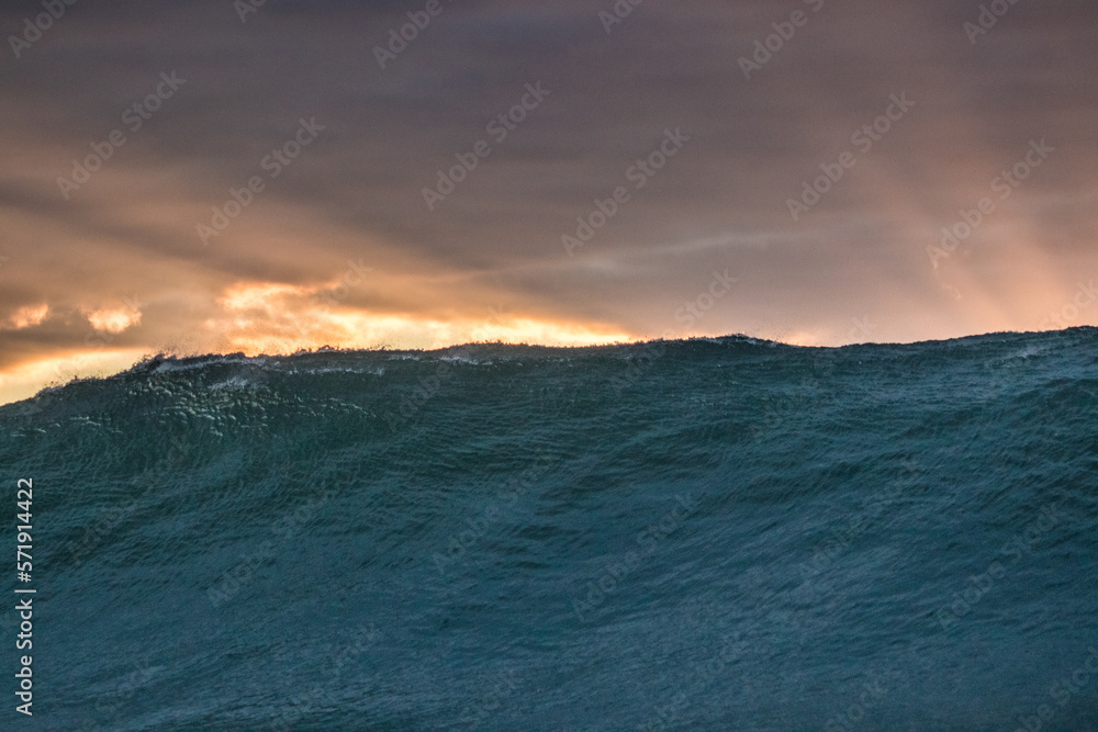 Raios de sol, sol nascendo atrás da onda no mar