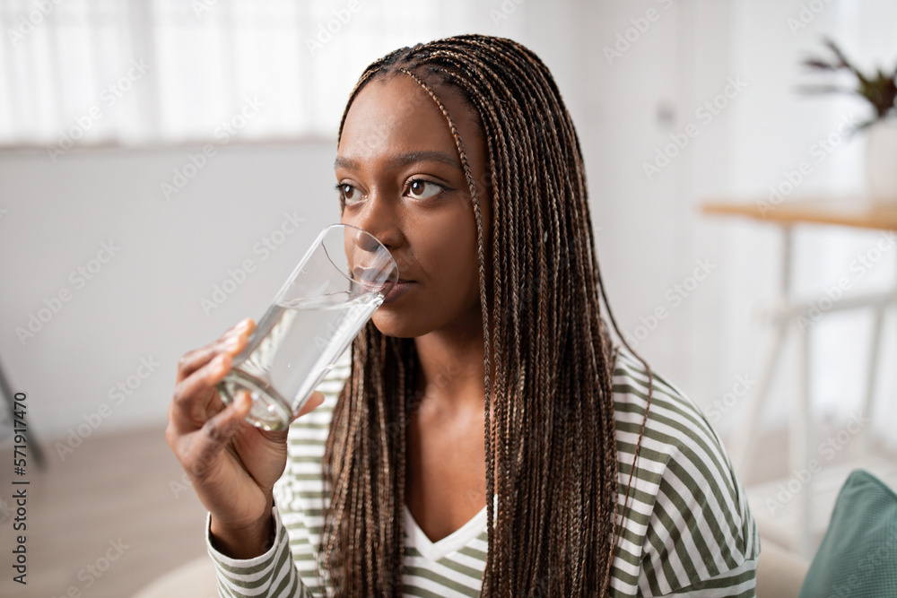 Closeup of young black woman drinking water at home Closeup of young black woman drinking water at home