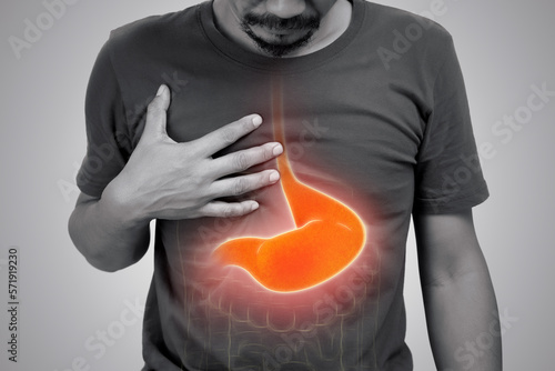 Asian man suffering from gastritis on gray background. photo