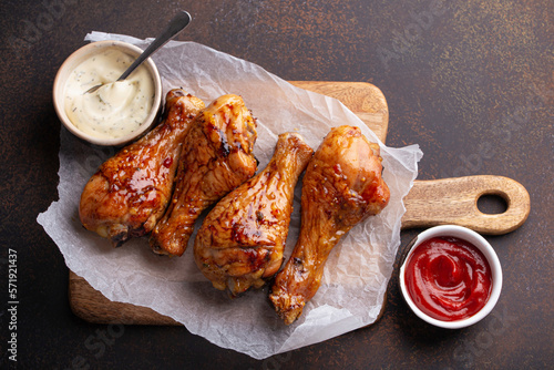 Roasted chicken drumsticks on paper, ketchup and mayonnaise