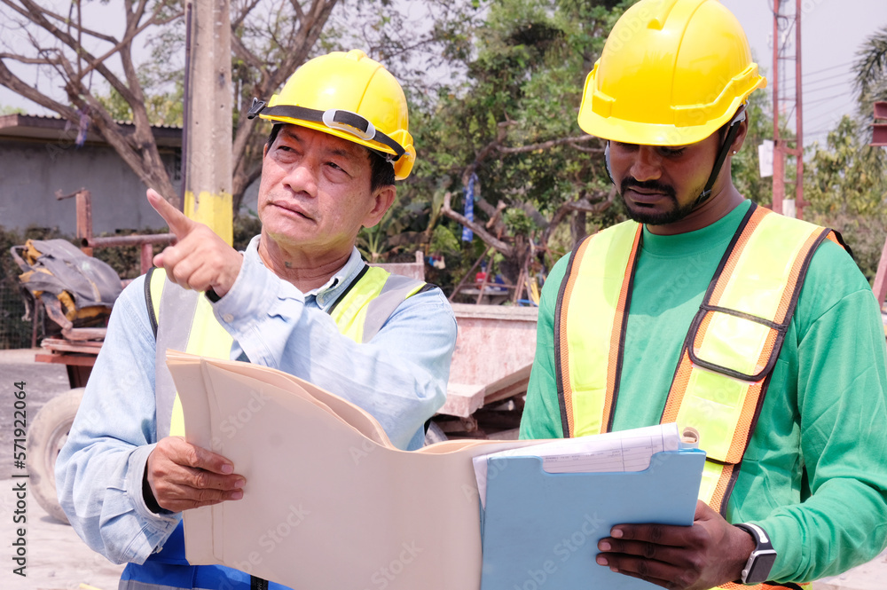 Fototapeta premium Male engineer in safety helmet inspecting construction drawings at construction site building construction concept.
