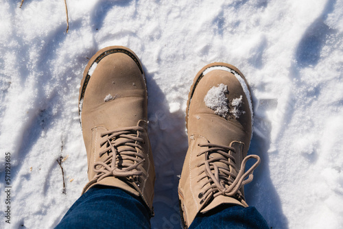 First person view of feet in women's boots in snow. Snow on beige boots during a winter walk