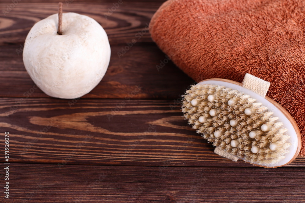 Brush for dry massage on wooden table with towel, lifestyle staging