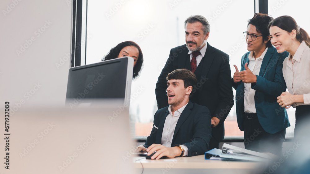 A team of exclusive diversity businesspeople are gathered together in an office, excitedly watching their accomplishment on a laptop computer. Idea for fostering strong teamwork in the workplace. A team of exclusive diversity businesspeople are gathered together in an office, excitedly watching their accomplishment on a laptop computer. Idea for fostering strong teamwork in the workplace.