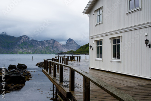 Norwegian house on the background of mountains. Tourist attraction in Norway. Amazing scenic outdoor view. Travel, adventure, relaxed lifestyle. Lofoten Islands