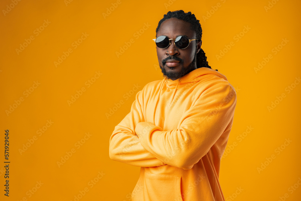 Close up of young african man in sunglasses standing against yellow background Close up of young african man in sunglasses standing against yellow background