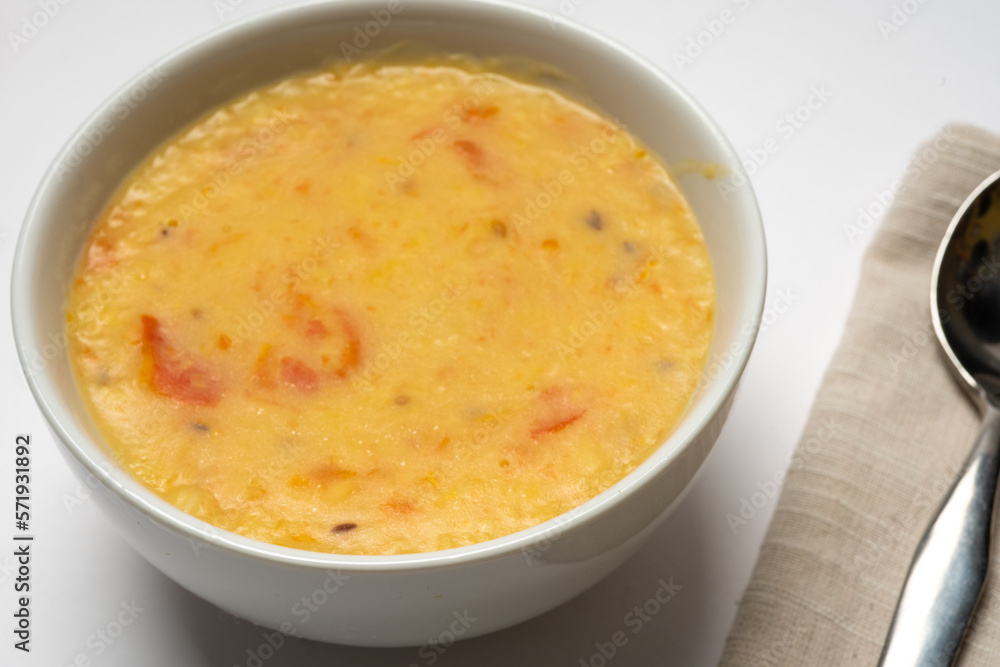 Homemade yellow split pea and mung soup, with onions and tomato,es , served in a white bowl on a white background. Close-up. Homemade yellow split pea and mung soup, with onions and tomato,es , served in a white bowl on a white background. Close-up.