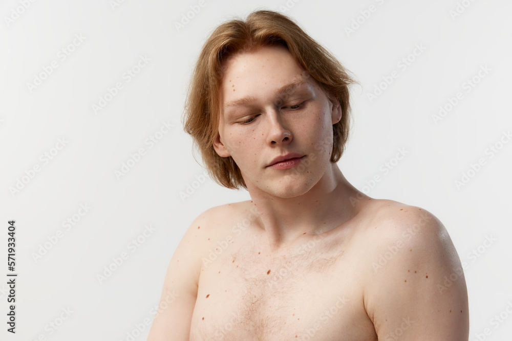 Natural make beauty. Moles on body. Portrait of young redhead man posing shirtless over grey studio background. Concept of men's health, body and skin care, hygiene and male cosmetology Natural make beauty. Moles on body. Portrait of young redhead man posing shirtless over grey studio background. Concept of men's health, body and skin care, hygiene and male cosmetology