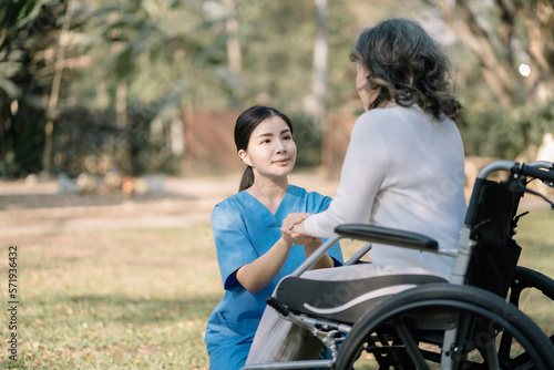 Young nurse holding hands of senior woman in wheelchair.