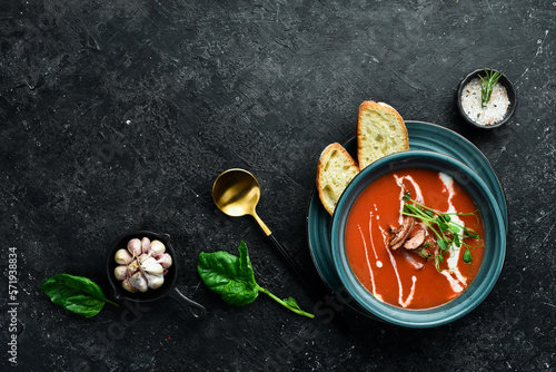 Tomato soup with bacon, onion and cream. Mexican cuisine. On a black stone background.