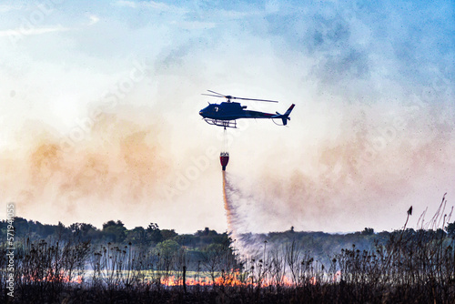 helicopter flying over a fire, helicopter putting out fire, helicopter with bambi bucket