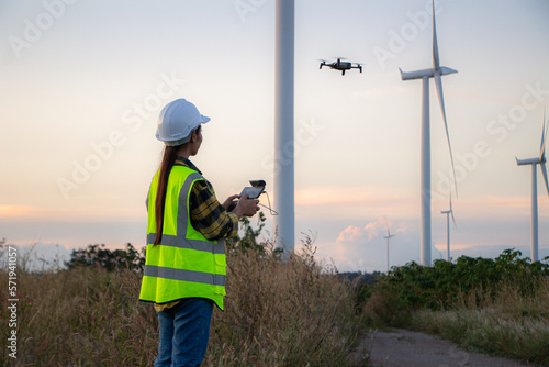 asian female engineer using drone for  inspection wind turbine farm in evening.