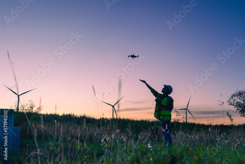 asian female engineer using drone for  inspection wind turbine farm in evening.