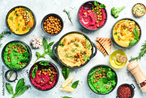 Traditional hummus, herb hummus, beetroot hummus. Vegetarian food. On a concrete gray background.