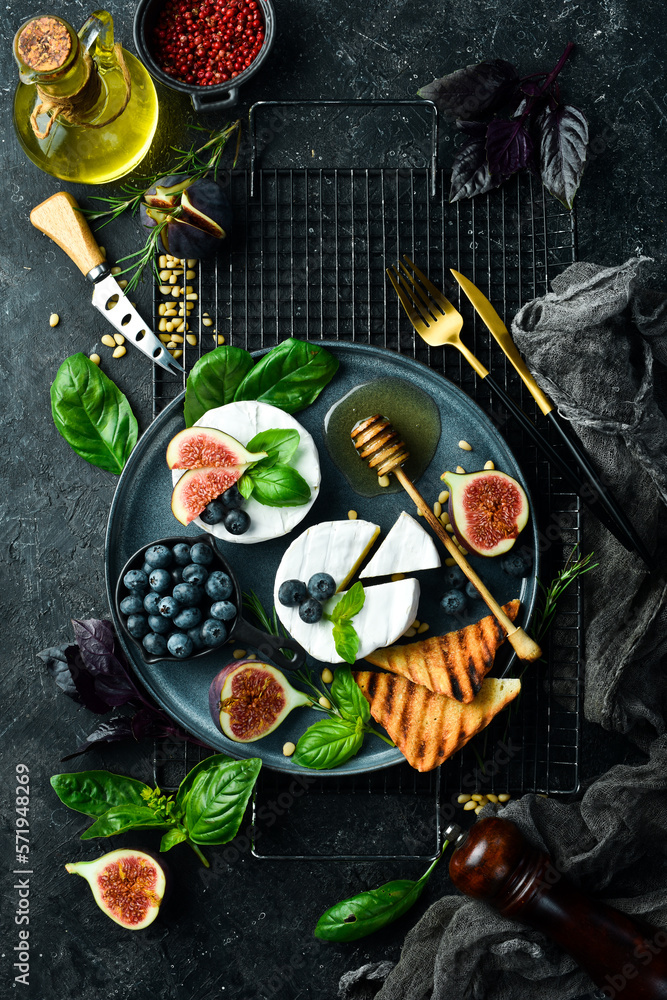 A plate with Brie cheese, with honey and figs. On a concrete background. Top view.