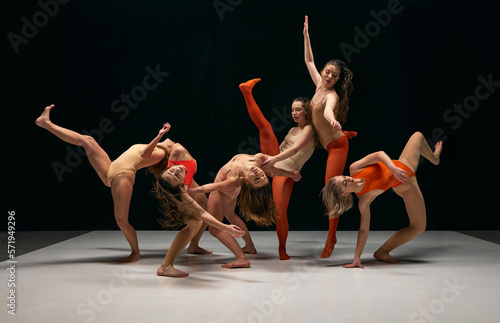 Extraordinary dance. Group of young flexible girls in bodysuits performing contemp over black background. Feelings and inner emotions. Concept of art, movement, youth, fashion, lifestyle, inspiration