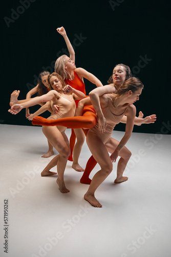 Fototapeta Naklejka Na Ścianę i Meble -  Extraordinary dance. Group of young flexible girls in bodysuits performing contemp over black background. Feelings and inner emotions. Concept of art, movement, youth, fashion, lifestyle, inspiration