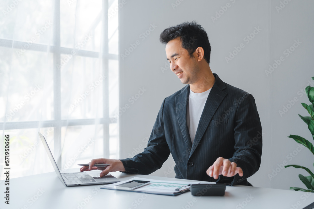 Young handsome asia business man in formal suit working with monthly report balance sheet and yearly tax of accounting to verify the account by an authorized auditor Young handsome asia business man in formal suit working with monthly report balance sheet and yearly tax of accounting to verify the account by an authorized auditor