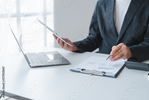 Fotografie Young handsome asia business man in formal suit working with monthly report bala