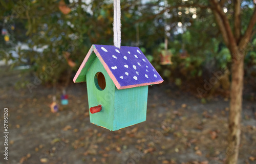 Small colorful wooden birdhouse hanging on a tree in garden, handmade bird feeder, DIY for kids