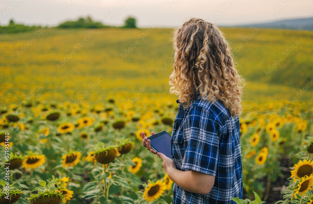 Curly-haired woman farmer using smart tablet at sunflower garden. Concept : Smart farmer. Using technology wireless device to study or research about Curly-haired woman farmer using smart tablet at sunflower garden. Concept : Smart farmer. Using technology wireless device to study or research about