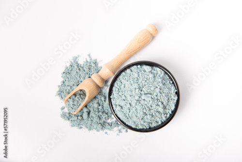 Blue spirulina powder in bowl and wooden spoon isolated on white background.
