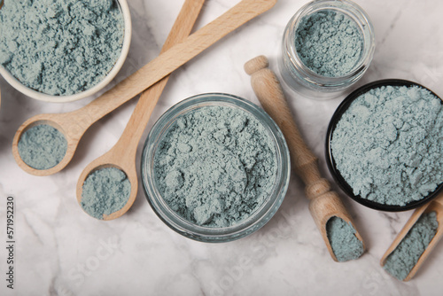 Blue spirulina powder in jars, bowls and spoons on a marble background. Natural superfood, vegan, healthy food supplement. Phycocyanin extract. Antioxidant. Place for text. Copy space.
