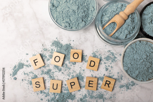 Blue spirulina powder in jars, bowls and spoons on a marble background. Natural superfood, vegan, healthy food supplement. Phycocyanin extract. Antioxidant. Place for text. Copy space.