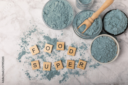 Fototapeta Naklejka Na Ścianę i Meble -  Blue spirulina powder in jars, bowls and spoons on a marble background. Natural superfood, vegan, healthy food supplement. Phycocyanin extract. Antioxidant. Place for text. Copy space.