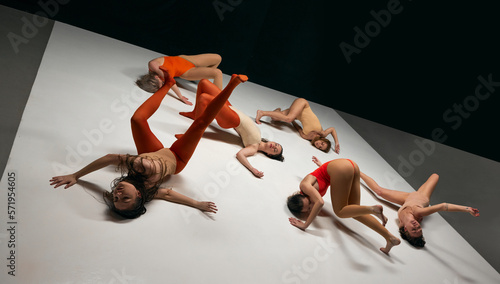 Experimental, contemporary dance style aesthetics. Young girls in bodysuits performing on stage on black background. On own position. Concept of art, movement, youth, fashion, flexibility, inspiration photo