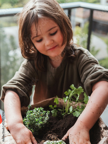 little girl planting aromatic plants at home