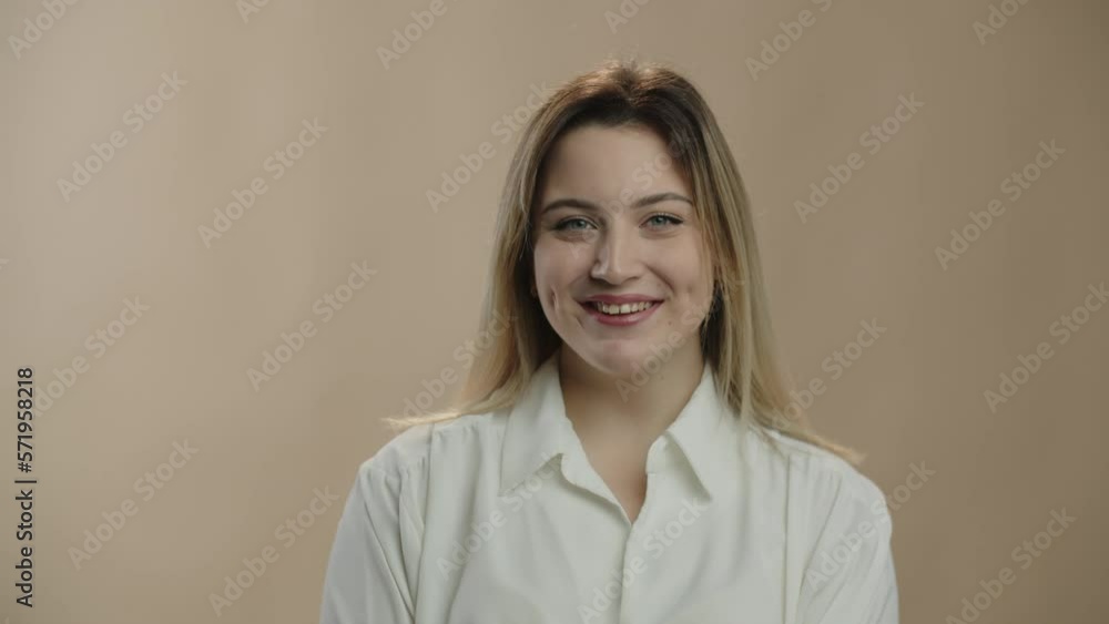 Attractive woman with light makeup laughing at camera. Front view of happy blonde girl posing with smile on beige background. Positive emotions Attractive woman with light makeup laughing at camera. Front view of happy blonde girl posing with smile on beige background. Positive emotions