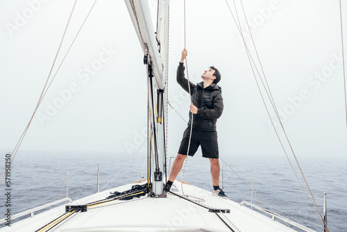 Focused man raising sail on yacht photo