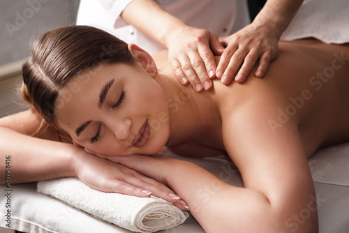 masseur massaging back and shoulder blades of young woman on massage table. Concept of massage spa treatments. Close-up