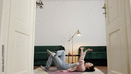 Pretty young Caucasian woman wearing casual clothes lie on floor and dancing with her hands. Side view. Concept of dance training and advertising