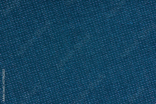 The background is made of blue material. Fabric for sewing clothes in a dark shade. Texture