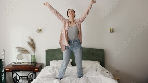 Happy young Caucasian woman funny dancing on bed. Slow motion. Concept of freedom and holiday
